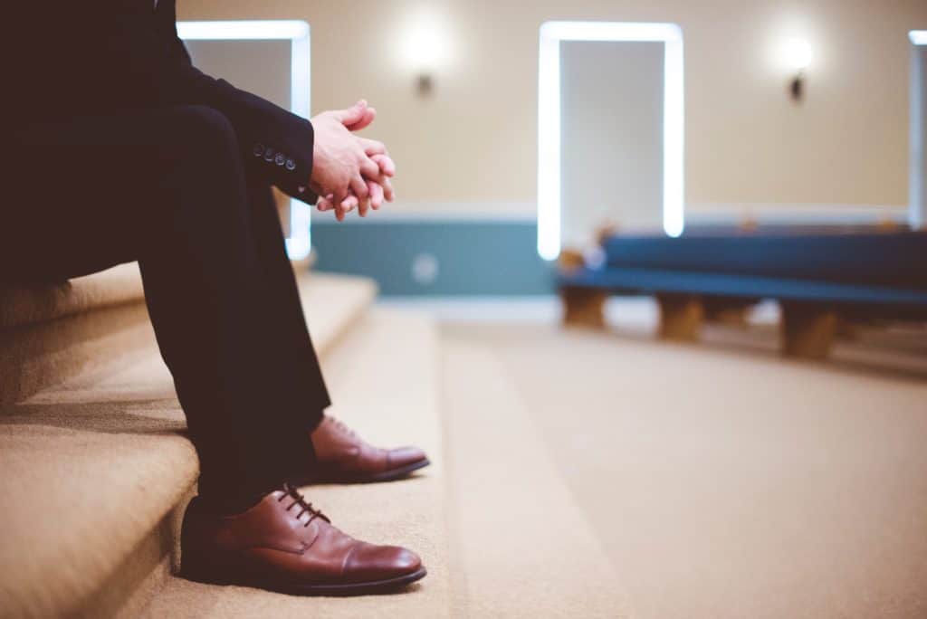 Man in brown shoes and black suit sitting and waiting